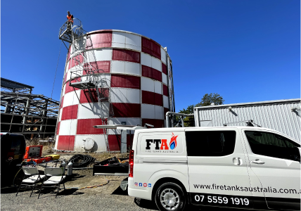 Fire Tanks Australia equipment and vehicles stationed near a large red and white water tank undergoing maintenance