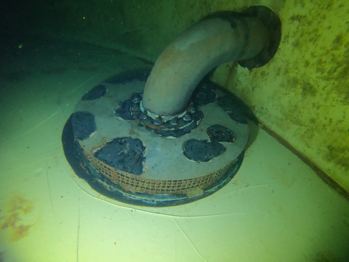 Underwater view of a corroded pipe connection and mesh cover inside a water tank, captured during a Fire Tanks Australia inspection.