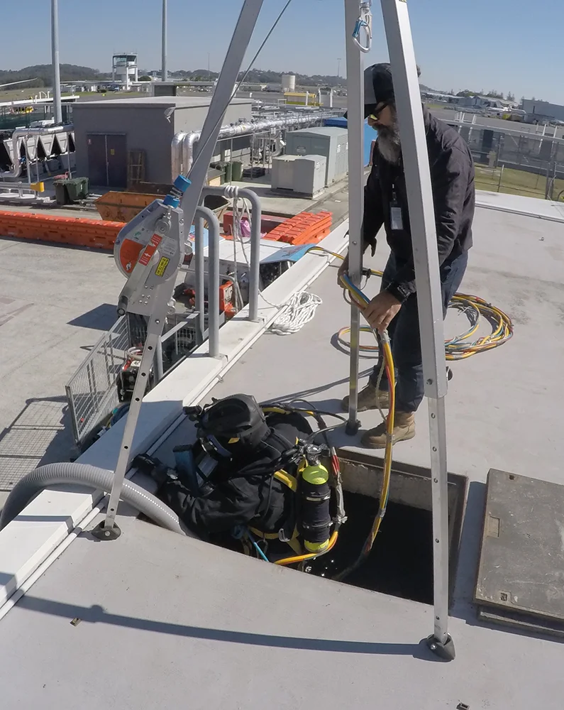Fire Tanks Australia diver entering an underground fire tank with the assistance of a technician using a safety hoist system.