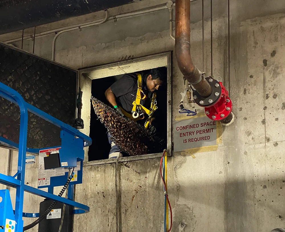 Fire Tanks Australia technician entering a confined space for fire tank maintenance with safety harness and equipment.