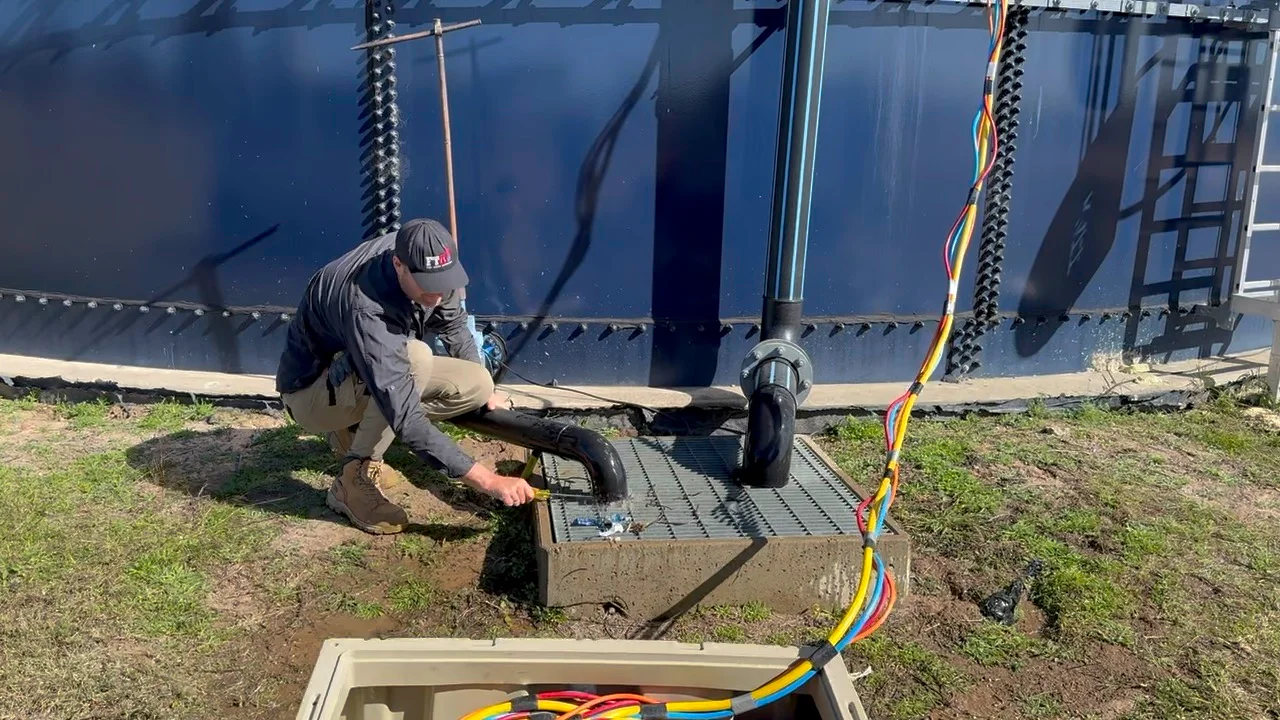 Technician inspecting a fire tank system with advanced piping and electrical connections by Fire Tanks Australia.