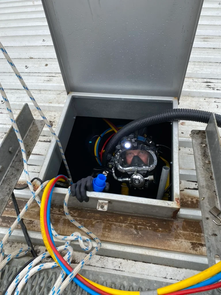 Fire Tanks Australia diver emerging from an underground fire tank access hatch with safety equipment.
