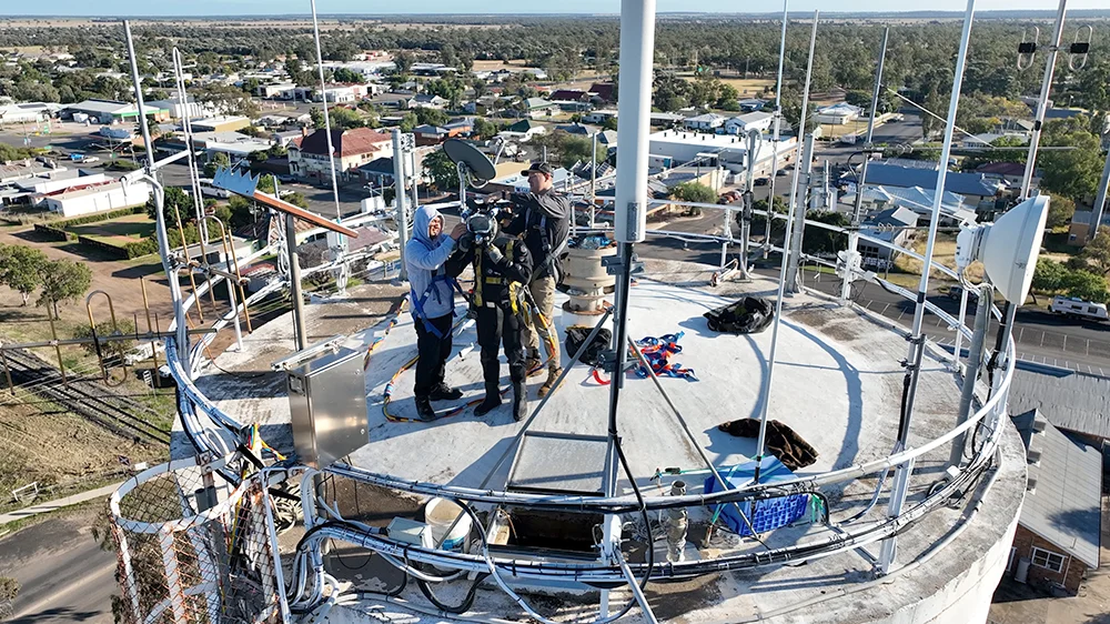Fire Tanks Australia team conducting high-altitude fire tank maintenance and inspection with safety equipment.