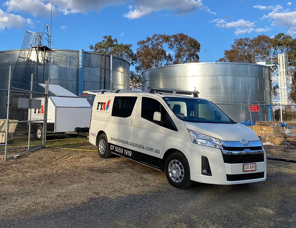 Fire Tanks Australia van and equipment trailer on-site for maintenance of large industrial fire water tanks.