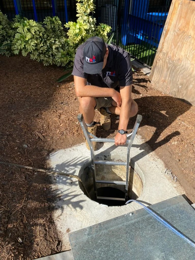 Fire Tanks Australia technician inspecting an underground fire tank entry point for maintenance.