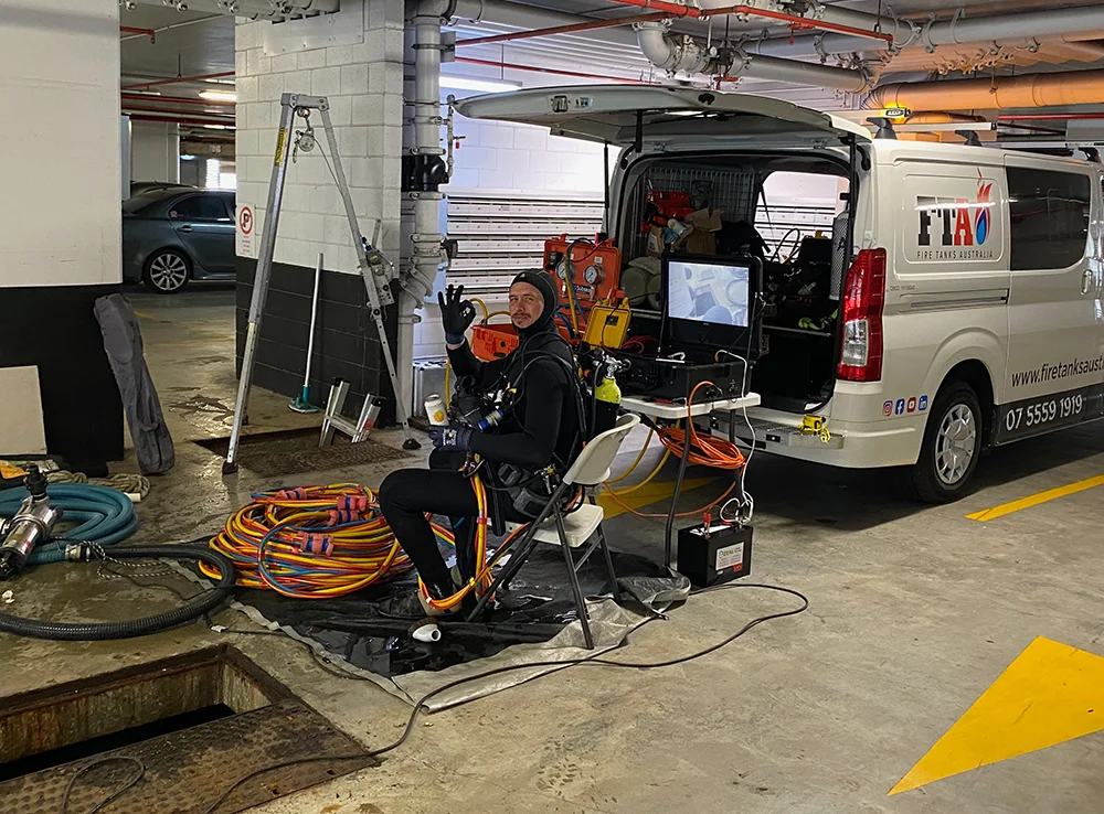 Fire Tanks Australia technician in a parking garage preparing for underground fire tank inspection with mobile equipment.
