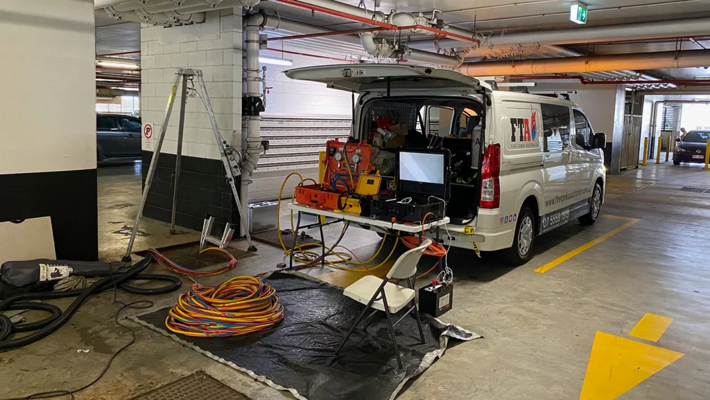 Fire Tanks Australia van parked in an underground carpark, set up with equipment, hoses, and a monitor for tank inspection.