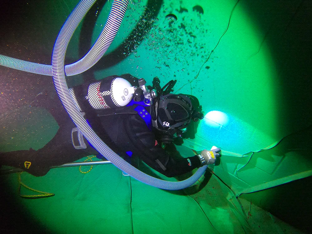 Fire Tanks Australia diver inspecting the interior of an underwater fire tank with specialized lighting and safety equipment.